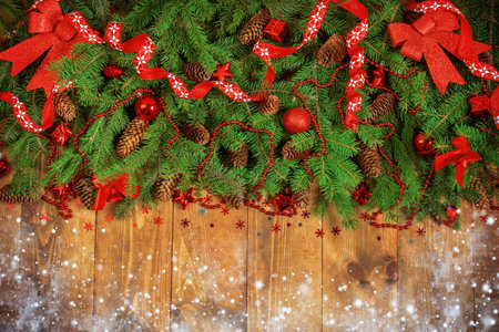 Christmas Border - fir branches with red baubles, bells and snowflakes on a wooden background.