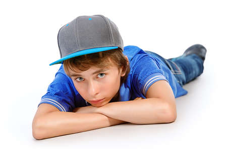 Portrait of a smiling teenage boy lying on a floor. Studio shot. Teen fashion. Isolated over white.の写真素材