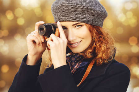 Autumn style. Beautiful smiling woman with bright foxy hair wearing beret and black coat photographs. Beauty, fashion.の写真素材