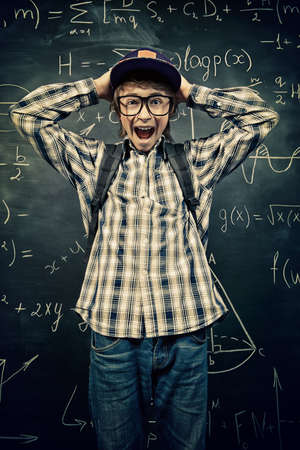 Education, high school, college. Portrait of a funny shouting student boy standing by a school blackboard.の写真素材