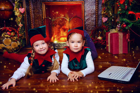 Two cute children in christmas elf costumes in a room beautifully decorated for Christmas. Time of miracles.の写真素材