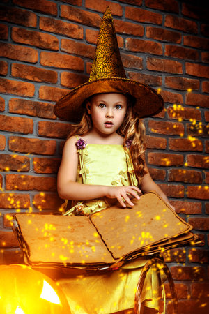 Cute little girl in witch costume with pumpkins. Halloween. Studio shot.の写真素材