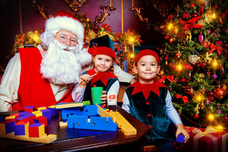 Santa Claus and the elves make gifts for children at Christmas. Workshop of Santa Claus. Christmas concept.の写真素材