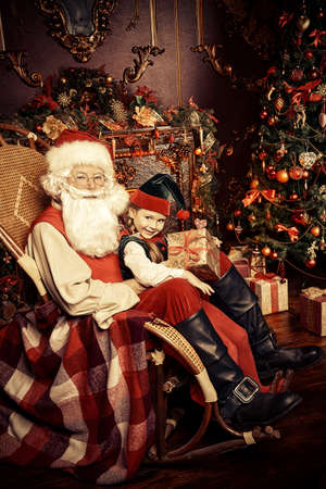 Santa Claus and the elf girl with gift box. Miracles on Christmas.の写真素材