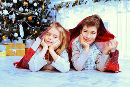 Happy funny children in pajamas playing near the Christmas tree and Christmas gifts. Luxurious Christmas decoration.の写真素材