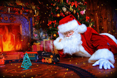 Happy Santa Claus playing with toys under the Christmas tree. Christmas concept. Magic time.の写真素材