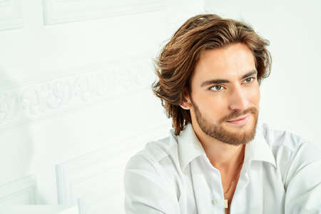 Handsome sexy man wearing white shirt posing in luxurious interior. Men's beauty, fashion model. Hair styling.の写真素材