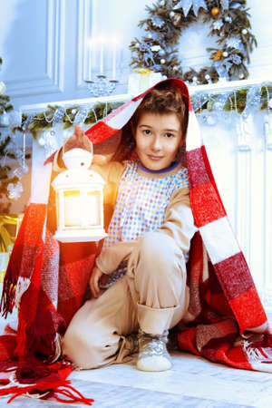 Happy nine year old boy in pajamas and a warm plaid waiting for Santa Claus and Christmas near the Christmas tree. Night befor Christmas.の写真素材