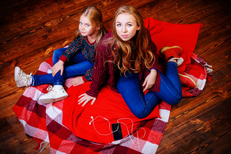Family concept. Two cute girls, older and younger sister sitting together on a floor. Children's...