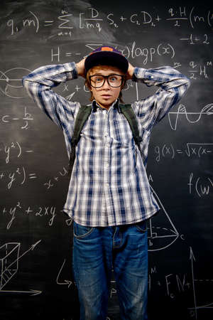 Education, high school, college. Portrait of a funny emotional student boy standing by a school blackboard.の写真素材