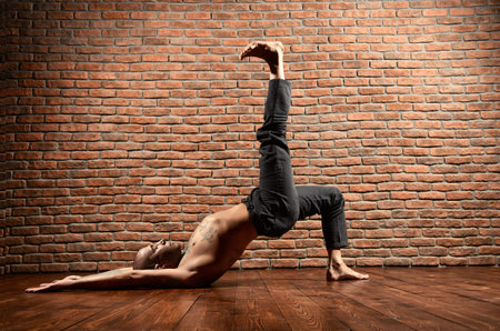 An experienced yoga instructor showing different yoga poses. Brick wall background. Healthy...