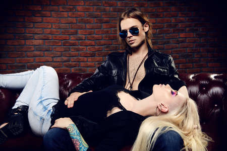 Passionate young woman lying on the lap of a brutal sexual man in a luxurious apartments. Love concept. Rock musicians.の写真素材