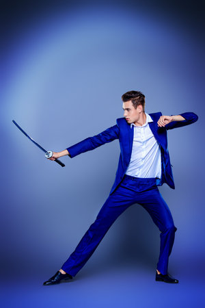 Businessman in a fighting stance with a sword in his hands. Struggle and competition concept.