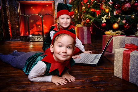 Two cute children in christmas elf costumes in a room beautifully decorated for Christmas. Time of...