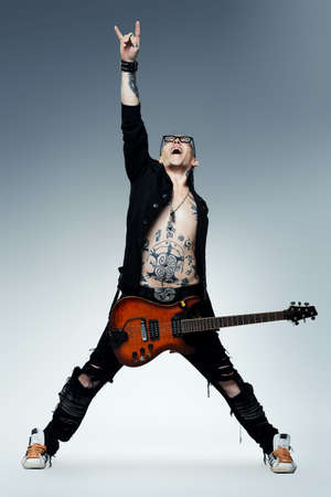 Excited rock musician is playing electrical guitar. Full length studio shot. Entertainment and musical concept.の写真素材
