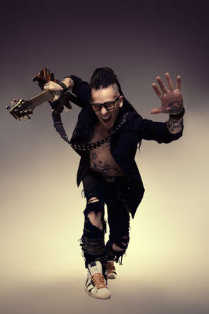 Excited rock musician is playing electrical guitar. Full length studio shot. Entertainment and musical concept.の写真素材