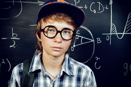 Education, high school, college. Portrait of a student boy standing by a school blackboard.の写真素材