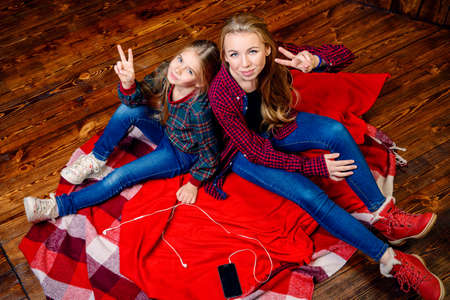 Family concept. Two cute girls, older and younger sister sitting together on a floor. Children's fashion.の写真素材