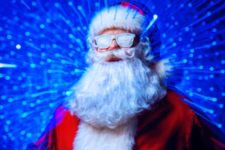 DJ Santa Claus in snowy glasses and headphones. Christmas songs and music. Disco lights in the background.の写真素材