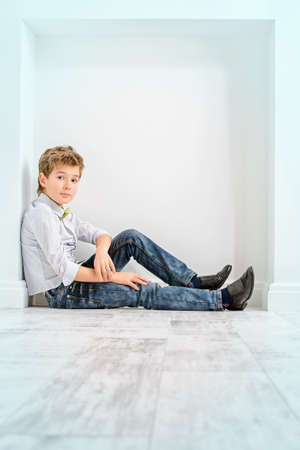Fashion concept. Cute nine year old boy in elegant clothes posing in a room with classic white interior. Kid's fashion.の写真素材
