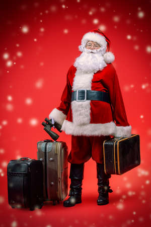 Christmas, tourist trip concept. Santa Claus with suitcases is going to travel around the planet. Christmas time. Time for miracles. Copy space.の写真素材