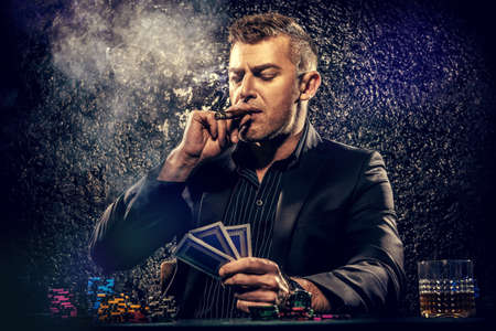 Rich gambler man with the cards and chips in casino. Gambling, playing cards and roulette.の写真素材