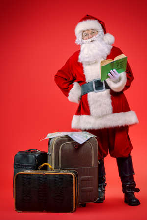 Christmas, tourist trip concept. Santa Claus with suitcases is going to travel around the planet. Christmas time. Time for miracles. Copy space.の写真素材