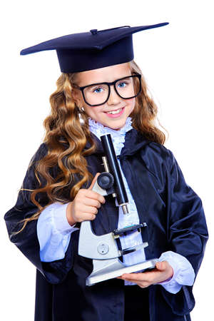 Portrait of a cute nine year old girl in an academic gown and hat holding a microscope. Educational concept. Isolated over white.の写真素材