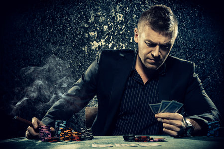 Rich gambler man with the cards and chips in casino. Gambling, playing cards and roulette.