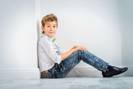 Fashion concept. Cute nine year old boy in elegant clothes posing in a room with classic white interior. Kid's fashion.の写真素材