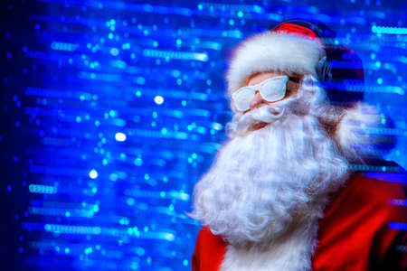DJ Santa Claus in snowy glasses and headphones. Christmas songs and music. Disco lights in the background.の写真素材