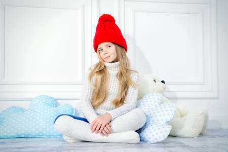 Cute little 7 year old girl wearing knitted winter clothes posing with her teddy bear. Children's fashion. の写真素材