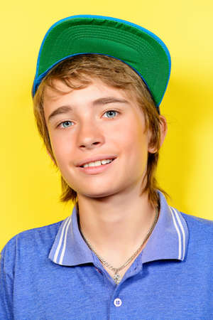Portrait of a smiling teenage boy over yellow background. Studio shot. Teen fashion.の写真素材