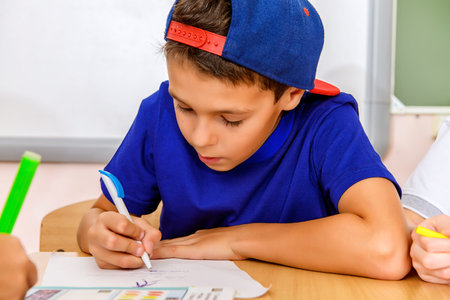 Portrait of a schoolboy studying during the lesson at school. Educational concept.