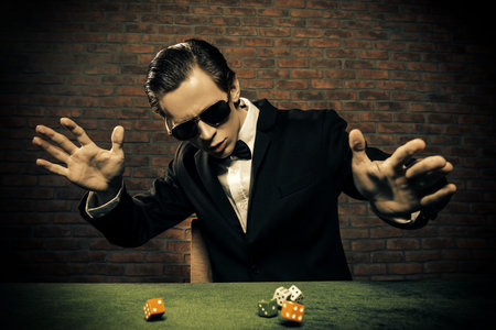 Excited gambling man throwing dice on a game table in a casino. Gambling, playing cards and roulette.の写真素材