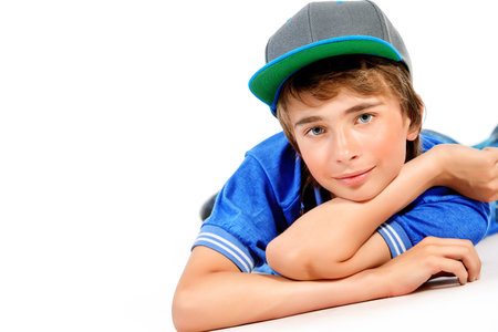 Portrait of a smiling teenage boy lying on a floor. Studio shot. Teen fashion. Isolated over white.の写真素材