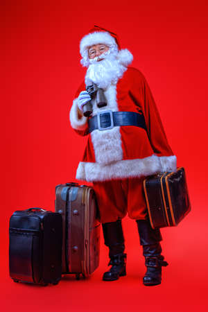 Christmas, tourist trip concept. Santa Claus with suitcases is going to travel around the planet. Christmas time. Time for miracles. Copy space.の写真素材