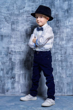 Cute little boy in elegant clothes and a hat. Be like daddy. Kid's fashion. Full length portrait.の写真素材