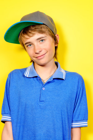 Portrait of a smiling teenage boy over yellow background. Studio shot. Teen fashion.