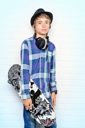 Modern teenage boy with skateboard. Studio shot. Youth culture.