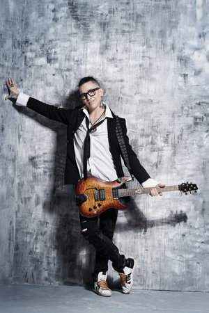 Excited rock musician is playing electrical guitar. Full length studio shot. Entertainment and...