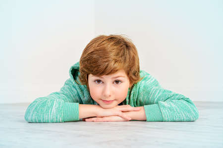 Pretty happy nine-year girl lying on a floor and smiling. Children's fashion. Education. Activity and child concept. Copy space.の写真素材