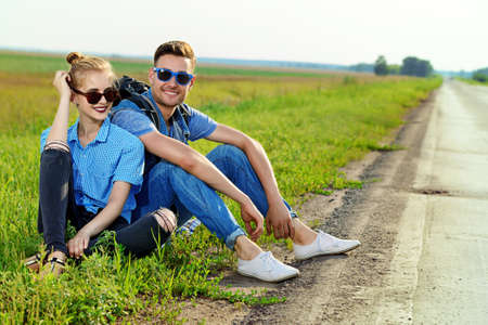 Happy young people sitting by the highway.の写真素材