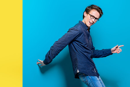 Cheerful young man posing over bright blue background.