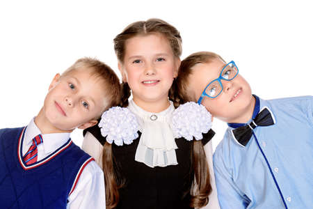 Portrait of three happy school friends posing together at studio. School uniform. Education. Isolated over white.の写真素材