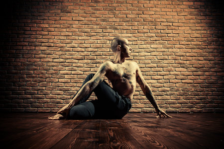 Mature man practicing yoga. Brick wall background.の写真素材