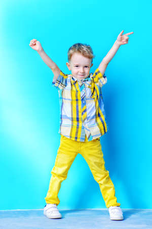Full length portrait of a cute funny little boy smiling at camera. Blue background. Copy space. Children fashion, summer concept.の写真素材