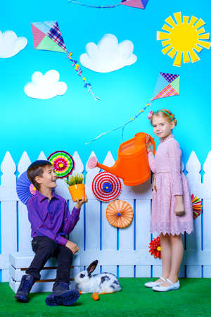 Two happy children play together in spring Easter decorations. Easter Bunny and painted eggs. Kid's fashion.の写真素材
