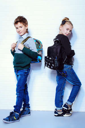 Children's fashion. Modern boy and girl posing together at studio. Education.の写真素材