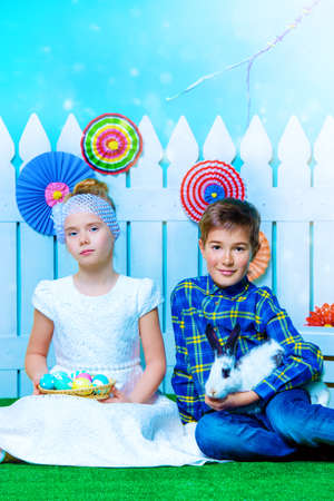 Two happy children play together in spring Easter decorations. Easter Bunny and painted eggs. Kid's fashion.の写真素材